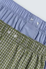 Pack de dos calzoncillos tipo bóxer de algodón en popelina, con cintura elástica y botones en la bragueta. Uno de los bóxers es de color celeste liso y el otro cuenta con estampado de cuadros en tonos verde y blanco.