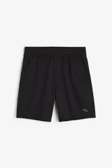 Short deportivo de tejido funcional en color negro, con cintura elástica, bolsillos laterales y aberturas en el bajo. Presenta un pequeño logo geométrico bordado en la pierna derecha.