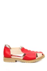 Zapato tipo sandalia plana de cuero liso en color rojo cereza con detalles en color crema. Presenta paneles laterales elásticos, suela dentada y diseño con aberturas.