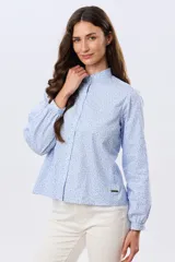 Camisa de algodón celeste con estampado floral pequeño, cuello mao, mangas largas con puños fruncidos y cierre frontal de botones.