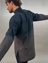 Camisa de lana color gris con cuello mao, corte recto y mangas largas con detalle texturizado. Presenta cierre invisible en el escote superior y tajos laterales.