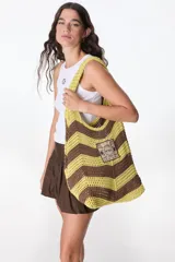 Bolso tejido a crochet con diseño a rayas horizontales en tonos marrón y beige. Tiene un parche cuadrado con el texto "Flowers Petra Club" y asas de hombro.