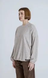 Sweater de tejido jaspeado color beige claro, con cuello redondo, mangas ranglán y elástico ajustable en el bajo.