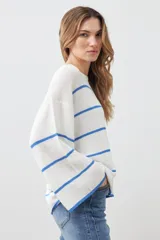 Sweater de punto color blanco con rayas horizontales azules, de corte holgado y mangas largas acampanadas.