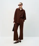 Pantalón sastre de corte wide leg en tejido crepé color marrón chocolate. Presenta una silueta recta y fluida, con cintura elástica y lazo ajustable para un calce cómodo.