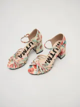 Sandalias de taco alto ancho con diseño retro, confeccionadas en charol negro. Presentan tiras delanteras múltiples entrelazadas, talón cerrado y una correa fina ajustable al tobillo con hebilla metálica.