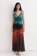 Vestido largo de tirantes finos con escote en V, caracterizado por un diseño degradado en tonos turquesa, negro y rojo. Presenta un frunce central en el torso que aporta textura y una falda amplia con caída fluida.