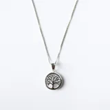 Conjunto de collar y aros con dije circular que presenta un diseño de árbol de la vida calado sobre una base de nácar, elaborado en plata.