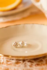 Aros tipo broquel de porcelana blanca con diseño de lunares en lustre de oro. Piezas artesanales horneadas a alta temperatura con detalles en oro.