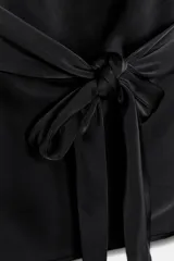 Top de tejido satinado color negro, con cuello halter anudado en la nuca y escote drapeado.
