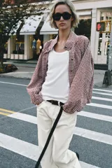 Chaqueta de manga larga con estampado a cuadros vichy en tonos marrón y blanco, cuello camisero, cierre frontal de botones, puños elásticos y cordón ajustable en el bajo.