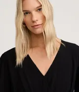 Blusa color vino tinto, con escote cruzado en V, mangas tres cuartos abullonadas con elástico en el puño y peplum ajustado en la cintura con lazo regulable.