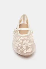 Zapato plano tipo bailarina color beige, con capellada de mesh bordado con flores y perlas. Tiene tira delantera con hebilla y punta redonda.
