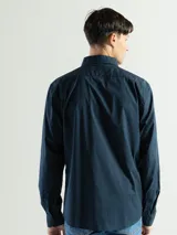 Camisa de manga larga color azul marino, confeccionada en algodón, con cuello abotonado (button-down) y un pequeño logo bordado en el pecho.