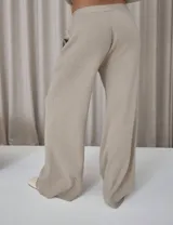 Conjunto de dos piezas compuesto por un cardigan entallado de tejido de punto con botones frontales y un pantalón de tiro medio con corte amplio y relajado. El diseño presenta una estética minimalista y versátil.