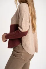 Sweater de tejido de punto con diseño de bloques de color en tonos beige, blanco roto y bordó. Presenta cuello redondo y mangas largas.