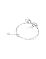 Brazalete rígido plateado con forma de lazo adornado con cristales transparentes.