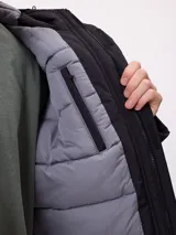 Campera técnica de invierno marca Rusty, color negro, con capucha ajustable, cierre frontal con solapa y bolsillos laterales. Presenta logo de la marca estampado en blanco en la manga y en el pecho.