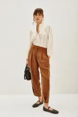 Pantalón sastrero de tiro alto, color blanco, confeccionado en cupro y viscosa. Presenta pinzas delanteras, bolsillos y ajuste elástico en el tobillo.