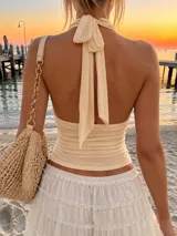 Top blanco de tul con diseño halter, escote pronunciado en V y detalles fruncidos en el cuerpo.
