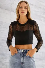 Blusa crop top negra con mangas largas de encaje y corpiño estructurado.