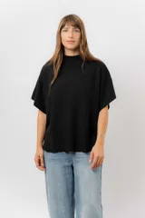 Sweater de tejido de punto color negro, con cuello semi alto y mangas cortas amplias. Presenta una silueta relajada y caída fluida.