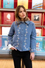 Chaqueta de lana merino hervida color marrón, con cuello camisero y botones forrados. Presenta bordados artesanales en color ocre que decoran el cuello, el frente y los puños.