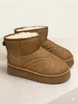Pantubota de caña baja color camel, con exterior de cuero sintético y costuras decorativas que forman un diseño geométrico. Cuenta con interior forrado en piel sintética y suela de plataforma dentada.