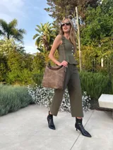 Cartera tipo bandolera de gran tamaño, confeccionada en cuero sintético con acabado desgastado. Cuenta con una asa corta fija, una correa larga regulable y extraíble, y una placa metálica con la marca en la parte frontal.