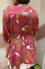 Blusa de calce holgado con estampado floral en tonos marrones, fucsias, naranjas y blancos. Tiene escote en V con doble lazo ajustable y mangas 3/4 con volumen.