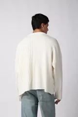Sweater negro de calce relajado con diseño de textura combinada, presentando un lado liso y otro con tejido de ochos. Cuenta con cuello redondo y una etiqueta decorativa en el frente.