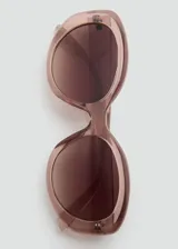 Lentes de sol con montura de pasta en color rosado translúcido y diseño ovalado. Lentes con protección UV y acabado degradado.
