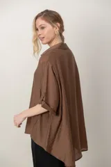 Camisa oversize de seda negra, con cuello camisero, cierre frontal con botones y mangas cortas con vuelta.