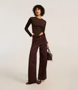 Pantalón wide leg color marrón confeccionado en sarga con pespuntes contrastantes, bolsillos delanteros y traseros, cintura alta con trabillas y cierre con botón y cremallera.