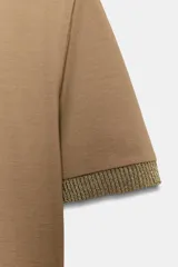 Camiseta de cuello redondo y manga corta, con detalle de tejido de punto brillante en los bordes de las mangas.