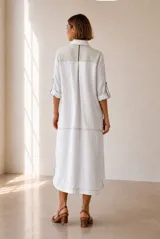 Vestido midi chemise de lino color beige, con cierre frontal de botones, cuello camisero, mangas cortas con vuelta y detalles en marrón oscuro en la botonera y los hombros.