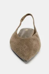Zapato plano tipo destalonado confeccionado en serraje, con diseño de punta fina y tira trasera ajustable con hebilla metálica.