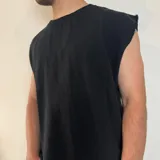 Musculosa de tejido de punto en color negro, con corte oversize y terminaciones desflecadas en las sisas.