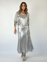 Conjunto plateado brillante de top con breteles finos y pollera larga con efecto mojado.