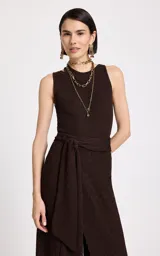 Top musculosa de tejido de punto color marrón chocolate, con cuello redondo, sisas amplias y detalle de corte asimétrico en el hombro izquierdo. Presenta un patrón texturizado en toda la prenda y dobladillo con ribete acanalado.