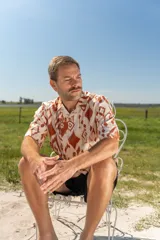 Camisa de manga corta con estampado abstracto en tonos naranja y blanco, cuello americano y botones de madera.