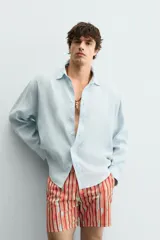 Camisa de corte relajado confeccionada en tejido de lino, con cuello solapa, manga larga con puños abotonados y cierre frontal de botones.
