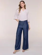 Pantalón wide leg de denim liviano gris, con tiro alto, presillas para cinturón, bolsillos laterales y corte recto de piernas anchas.