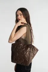 Bolso tote plateado, tipo shopper, con diseño acolchado. Forrado internamente en color negro.