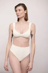 Conjunto de bikini color crema con textura acanalada, compuesto por un top con breteles anchos y una bombacha de tiro alto.