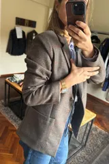 Blazer femenino forrado de corte tradicional, levemente entallado en la cintura, con mini hombreras. Presenta un diseño de cuadros, botón metálico con escudo y costuras en tono contraste.