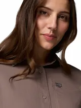 Camisa de trekking Columbia de manga larga, color marrón, con cuello clásico, cierre frontal de botones y bolsillo en el pecho con logo de la marca. Diseño técnico con tecnología Omni-Shade y Omni-Wick.