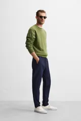 Pantalón de corte slim fit confeccionado en tejido elástico, con cintura elástica, cierre frontal con cremallera y botón, bolsillos laterales y bolsillos traseros de vivo.