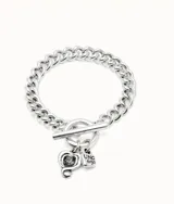 Pulsera de cadena de eslabones gruesos bañada en plata, con cierre de barra en T y dos dijes colgantes: uno en forma de corazón con un cristal negro incrustado y otro con el logo de la marca.