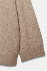 Jersey oversize color beige melange, confeccionado con lana, con cuello en V y manga larga.